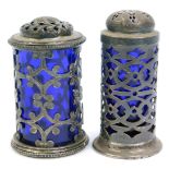 Two silver pepper pots, both with Bristol Blue glass liners, one with open scroll work body and scre