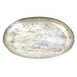 A Victorian oval pin tray, with repousse decoration of a putti drumming in a landscape setting, make