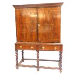 A William and Mary style walnut chest on stand, the outswept pediment over a pair of doors enclosing