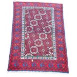 A Persian red ground rug, decorated with geometric medallions, within repeating geometric and floral