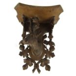 A Black Forest hanging wall shelf, with central stag's head motif, surrounded by acorn leaves, with