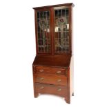 An Edwardian mahogany bureau bookcase, the out swept pediment over a pair of glazed and stained glas