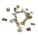 A silver charm bracelet, of chunky curb link form, with charms to include wishing well, bell, poodle