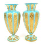 A pair of Bohemian pale blue and white flash glass vases, with gilt scroll decoration, on stepped fo