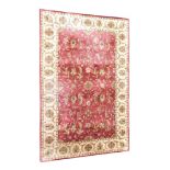 A machine woven silk and cotton Indian rug, with a Persian design of flowers, roundels, in deep red