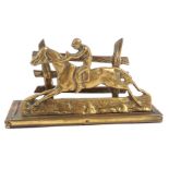 A brass letter rack, formed as a jockey riding with fence post back, 20cm wide, 10cm high.