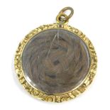 A Victorian memorial locket, the circular locket with gilded back, with scroll outer border and cros