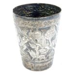 A late 19thC Indian white metal beaker, with repousse decoration of figures and wild animals within