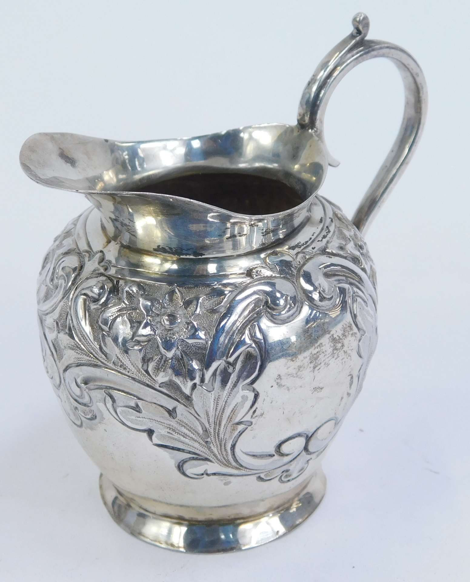 An Edwardian silver cream jug, of tapered ovoid form, with repousse decoration of flowering foliates - Image 2 of 3