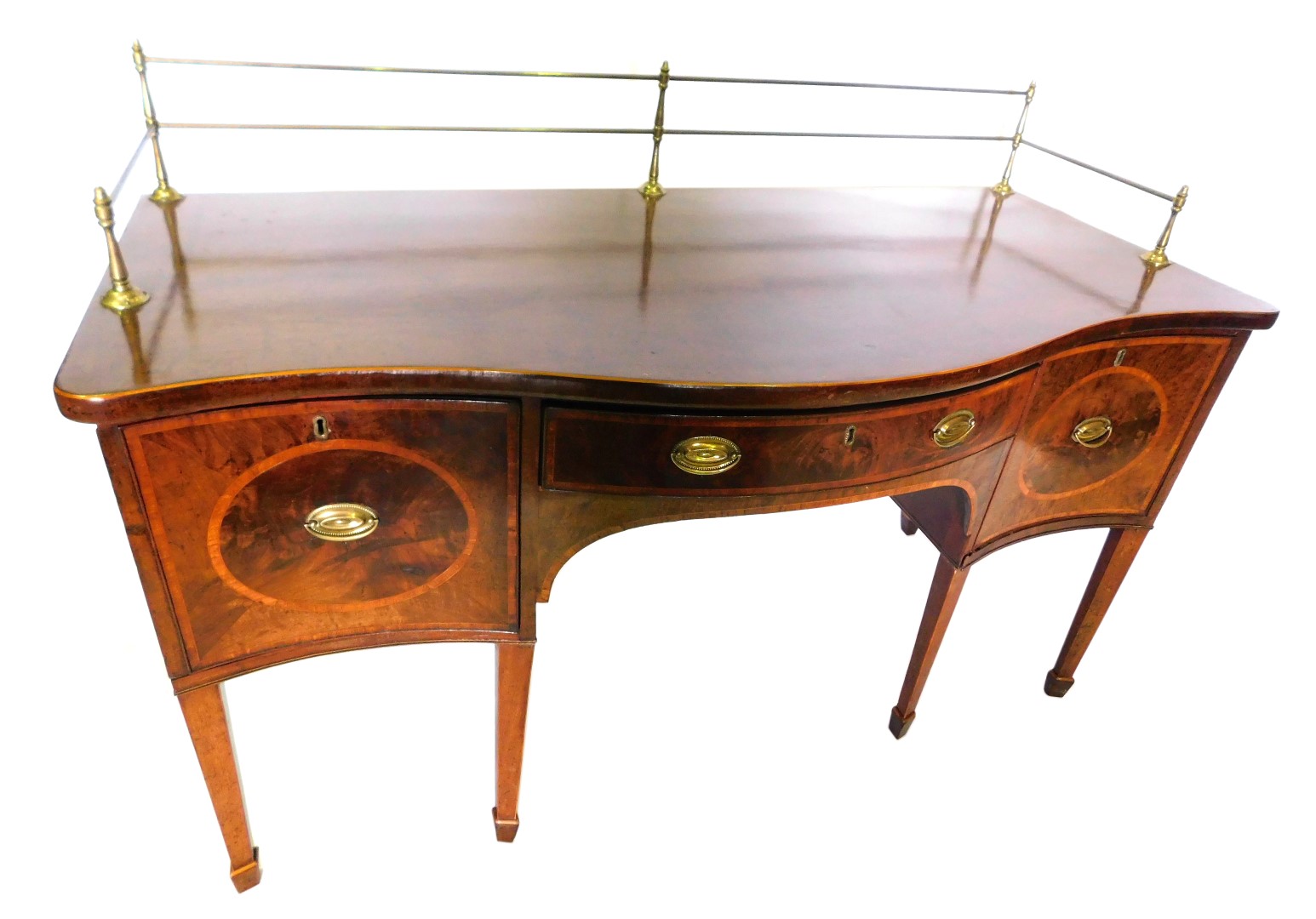 A George III mahogany and boxwood strung sideboard, the serpentine fronted top with a brass gallery,