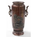 A Meiji period Japanese bronze vase, of twin handled cylindrical form, decorated in relief with a dr