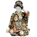 A Japanese Kutani porcelain figure of a seated geisha, decorated in red, blue, gilt, and black, 23cm