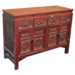 A Chinese red lacquered side cabinet, with an arrangement of drawers and cupboards, 96cm high, 125cm