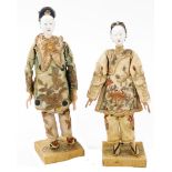 A pair of late 19thC Chinese porcelain opera dolls, modelled in silk costume, on silk covered spike