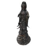 A Qing Dynasty bronze figure of Guan Yin, modelled standing, on a dragon fish, above a scrolling wav