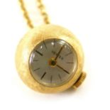 A Vertex globe pendant watch on chain marked 18ct, watch case marked with a female head.