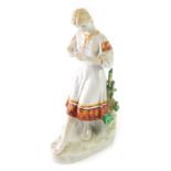 A Ukrainian Polonoye figure of a girl counting daisies, marked beneath, 37cm high.