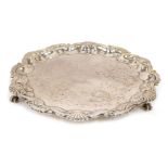 An Edward VII silver pie crust salver, etched with scrolls with central crest, on triple claw and ba