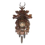 A Black Forest dancer and cuckoo clock, the pedimented case flanked by carved game, with stag finial
