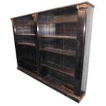 A late 19th/early 20thC ebonised bookcase, with two banks of adjustable shelves flanked by plain col