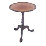 A walnut occasional table, in George III style, the piecrust shaped top on a leaf carved and turned