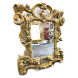 A 19thC gilt wood mirror, with entwined scroll rococo frame, 36cm x 30cm.