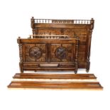 A late 19th/early 20thC French walnut bed head and foot, carved with scrolls, leaves etc. flanked by