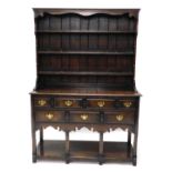 An oak dresser in 18thC style, the plate rack with three shelves on end supports, the base with a mo