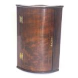 A small mahogany bow fronted walnut corner cabinet, with pierced brass butterfly shaped hinges, 72cm