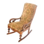 A late 19thC satin walnut rocking chair, with a padded back and seat, on turned supports.