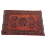 An Eastern rug, with a design of four lozenges and a medallion, in black on a red ground with multip