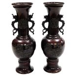 A pair of Meiji period Japanese bronze vases, of twin handled baluster form, relief decorated with b