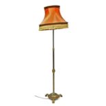 An early 20thC brass standard lamp, with a frill salmon pink coloured shade, 191cm high.