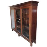 An early 20thC mahogany office bookcase, the outswept pediment over three sliding doors enclosing fo