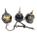 Three German Pickelhaubes, two bearing badges of the Prussian Eagle, in various condition.