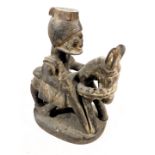 A late 19thC West African wooden carving, of a man in a headdress, mounted on a horse or donkey, and