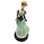 A Leonardo Collection figure of a lady in late nineteenth century costume, raised on a circular base