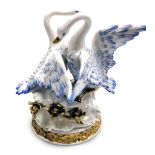 A continental porcelain figure group of a pair of courting swans, raised on a naturalistic base with