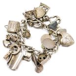 A silver charm bracelet, on a heart shaped padlock clasp, with safety chain, and twenty six charms,