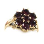 A garnet seven stone flower head ring, in a yellow metal mount, hallmarks worn, size M, 2.9g.