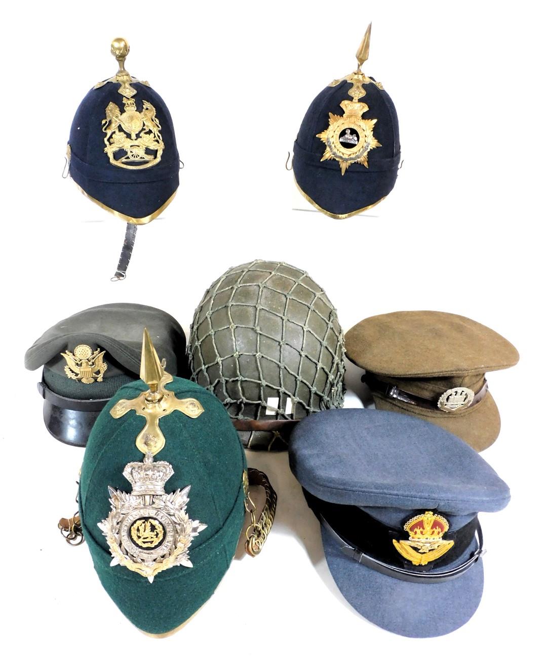 Three British Army helmets, with three regimental badges for the Royal Artillery, South Wales Border