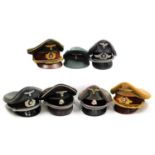 Seven German peaked caps, emblems include Gestapo, Luftwaffe, etc.