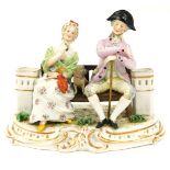 A Continental porcelain figure group, of two figures seated on a bench, depicting male and female wi