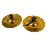 A pair of 1950s brass parade cymbals, with turned wooden handles, 18cm diameter.