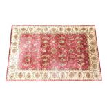 A machine woven silk and cotton Indian rug, with a Persian design of flowers, roundels, in deep red