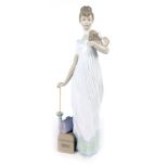 A Lladro porcelain figure of a lady, with travel case, parasol and dog, 35cm high.