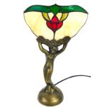 An Art Deco style table lamp, with a fluted Tiffany style glass top, with semi clad female, on bronz
