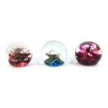 Three glass paperweights, comprising Selkirk Glass Sunburst number 198, Selkirk Red Miracle 29/500,