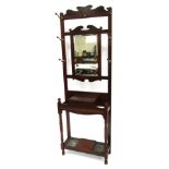 An early 20thC mahogany hall stand, the top with a scroll carved panel above an arrangement of seven
