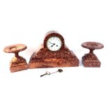 A 19thC French red marble mantel clock and garniture, the white Arabic dial with eight day movement,